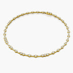 A yellow gold tennis necklace featuring baguette-cut and round-cut clear stones, arranged in a circular pattern on a light gray background.